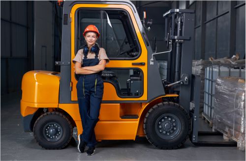 Worker standing in front of her forklift on national forklift safety day