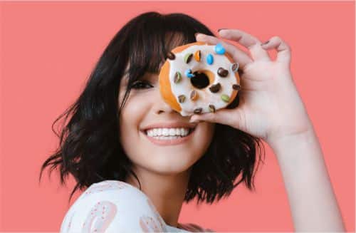 A woman looking though the hole in a donut for National Donut Day