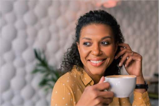 Woman smiling with a cup of coffee for International Coffee Day