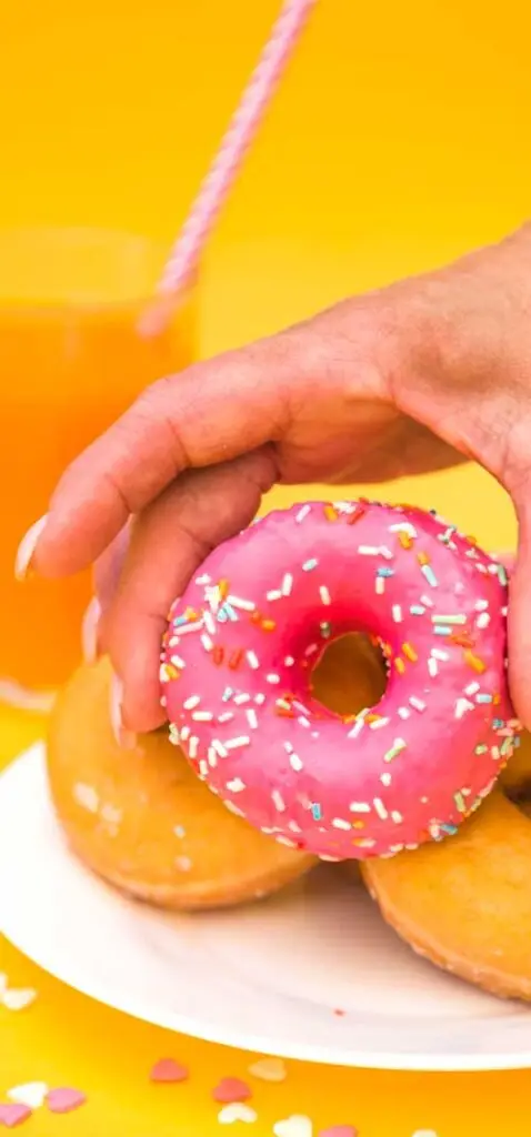 hand picking up donut from a plate