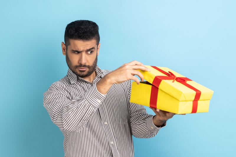 Employee peeking under the lid of a gift box hoping that it's not another bad employee gift
