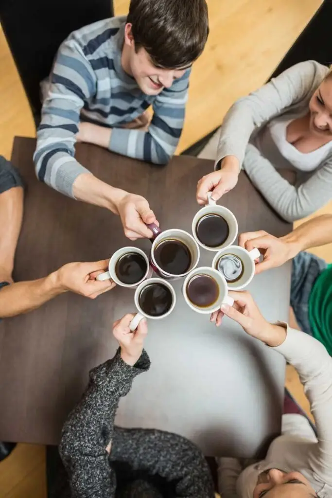 people holding up coffee cups