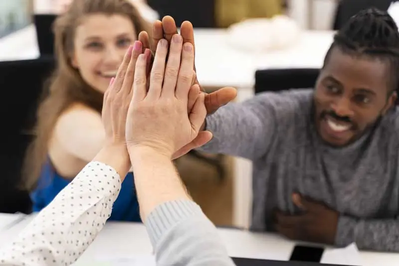 employees high five around table